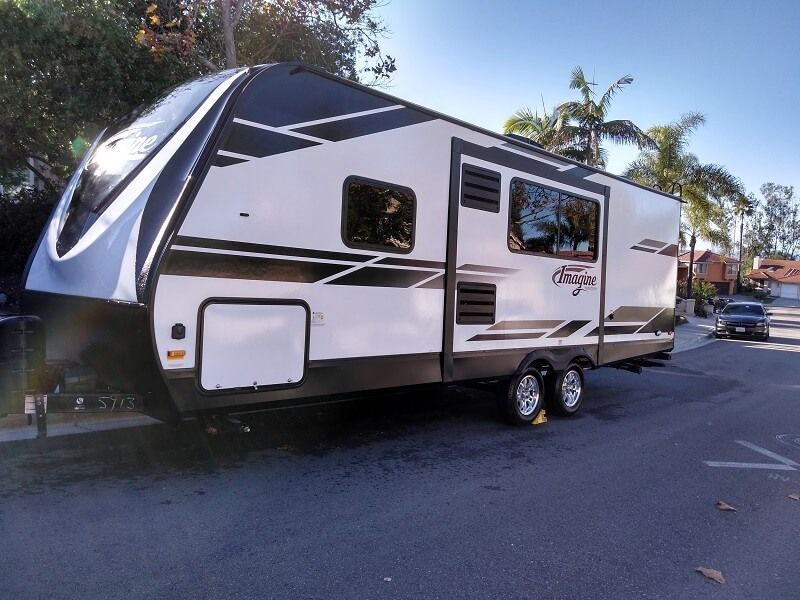 a white and black rv is parked on the side of the road