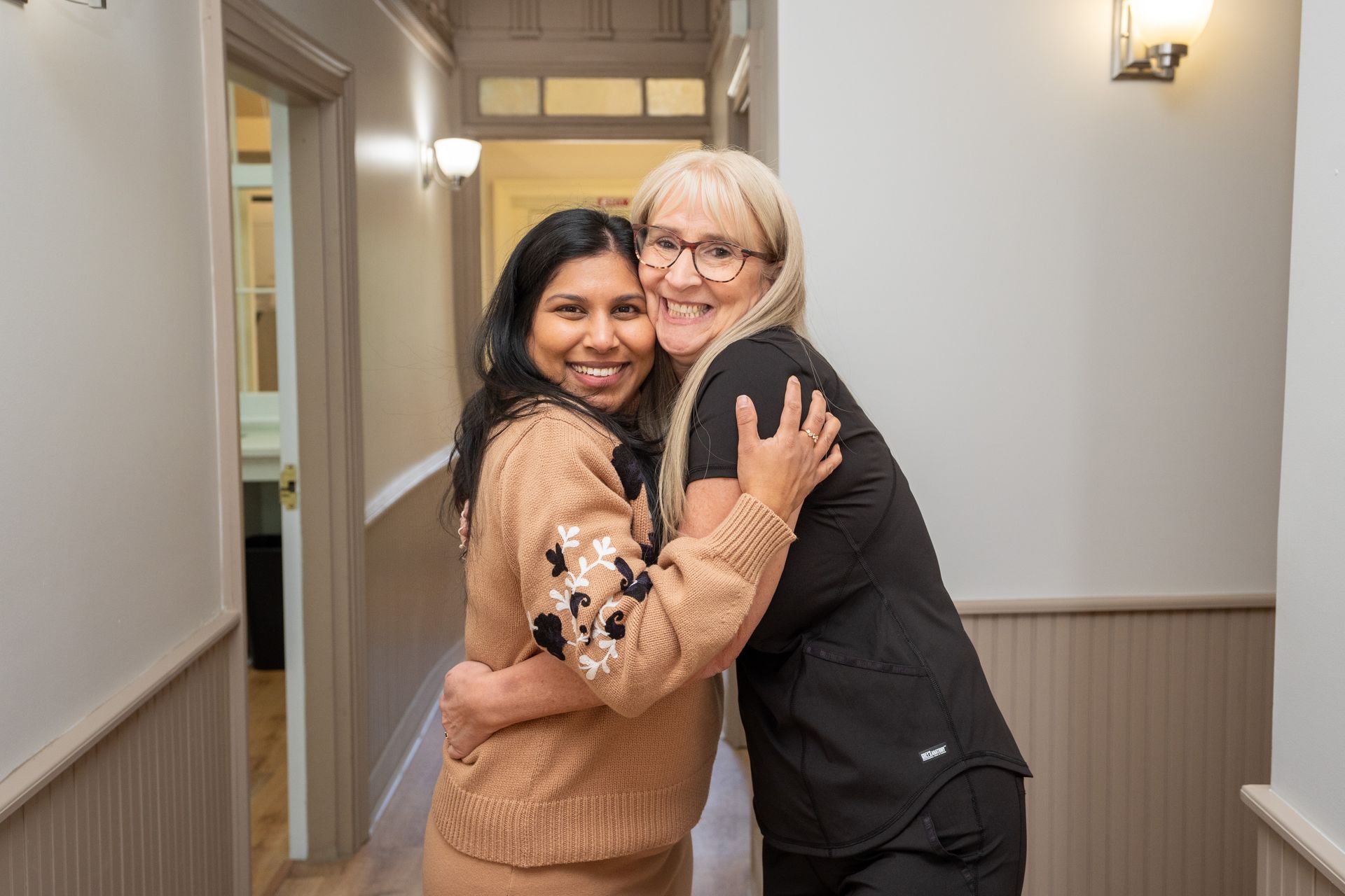 Blonde woman smiles, holding a yellow smiley face balloon with a Ferris wheel in the background.