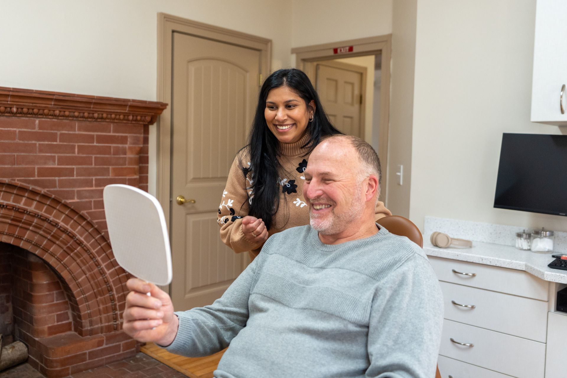 Blonde woman smiles, holding a yellow smiley face balloon with a Ferris wheel in the background.