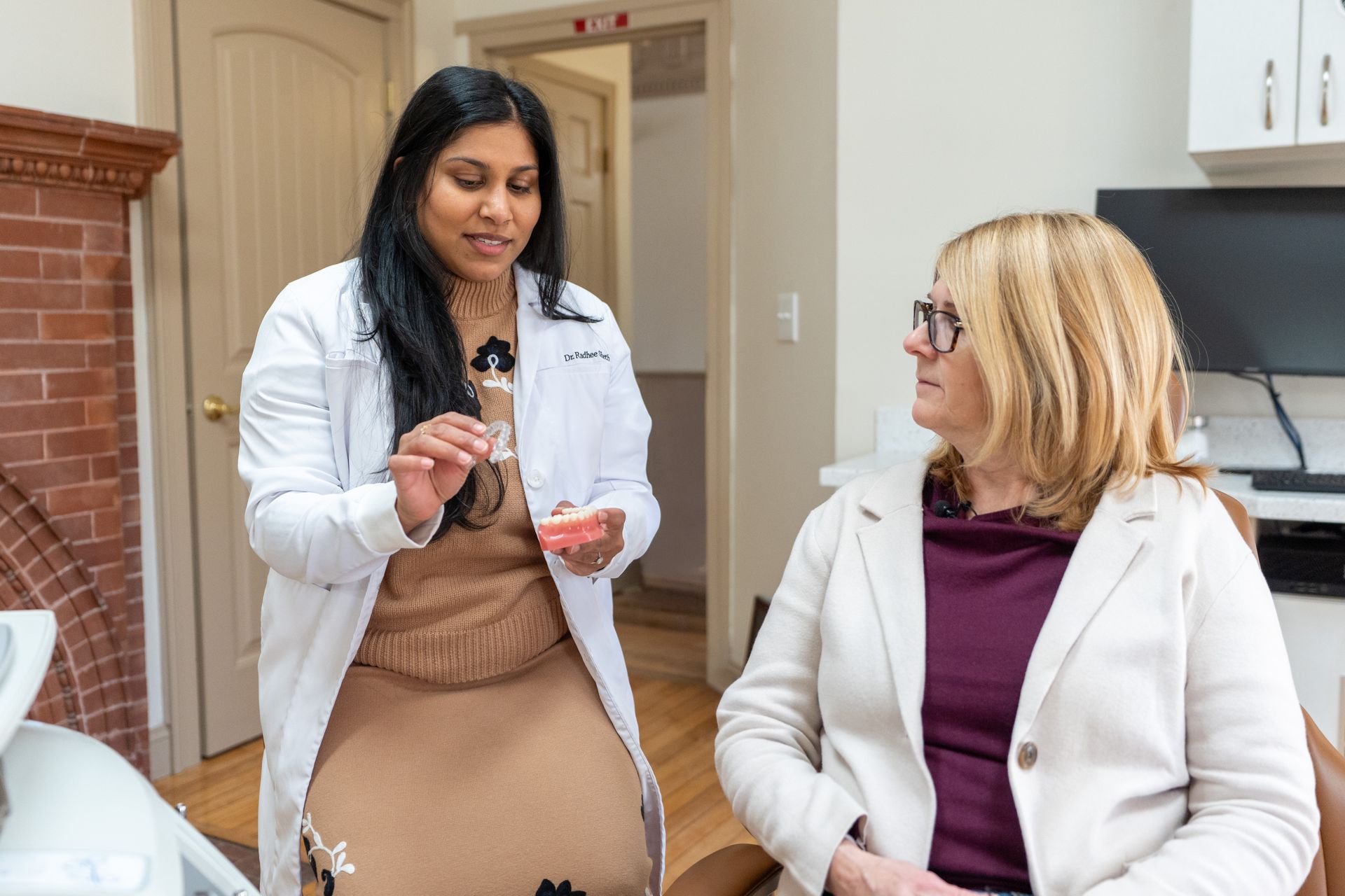 Woman holding clear aligner near teeth, smiling.