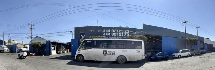 Un autobús blanco está estacionado frente a un edificio.