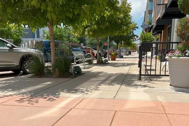 A commercial concrete walkway in front of Colorado businesses.