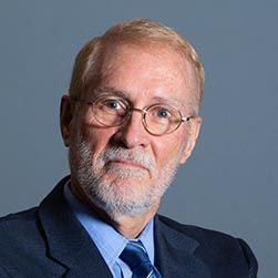 A man with a beard and glasses is wearing a suit and tie.