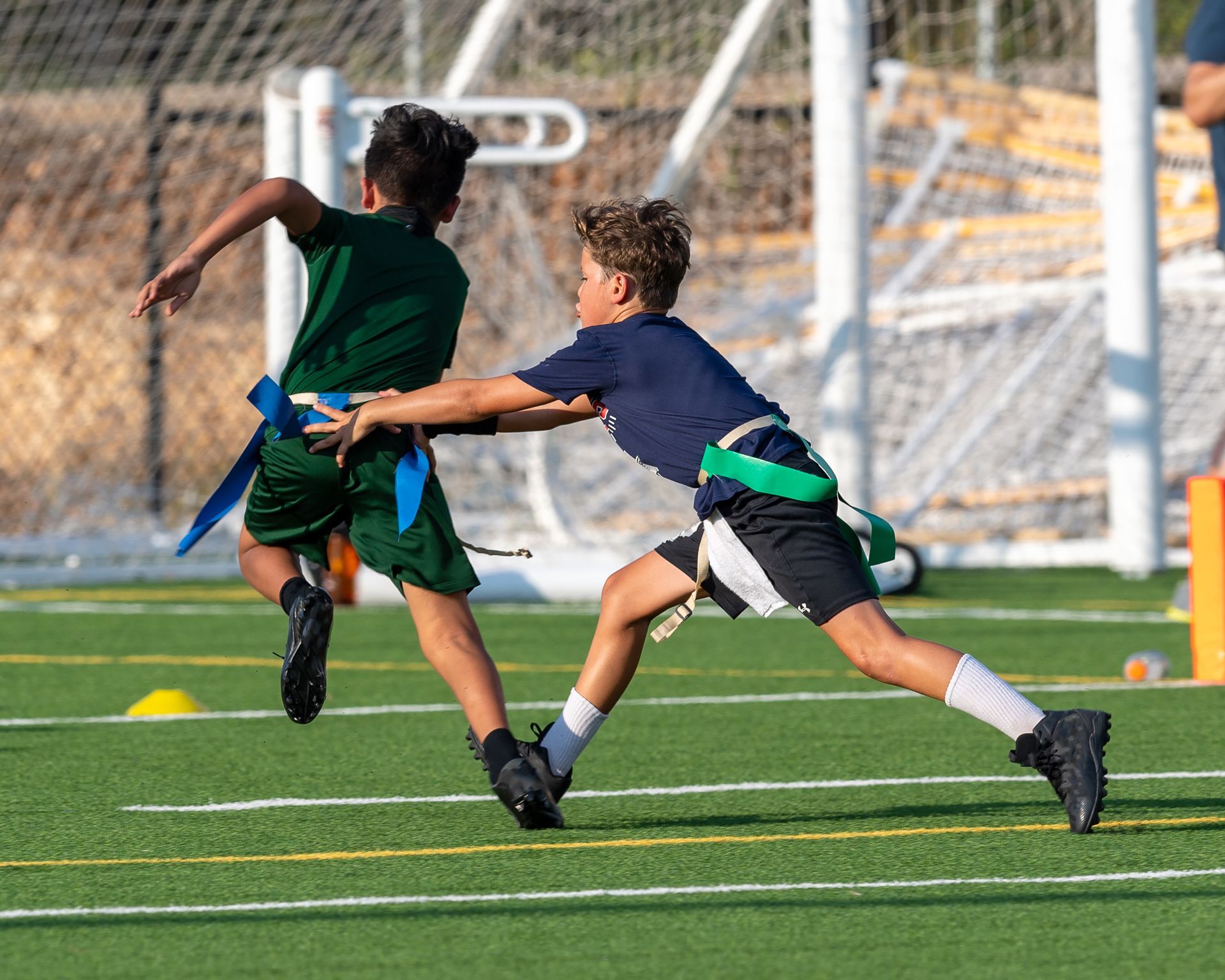 Football players huddle around a football, reaching hands together, blue sky backdrop.