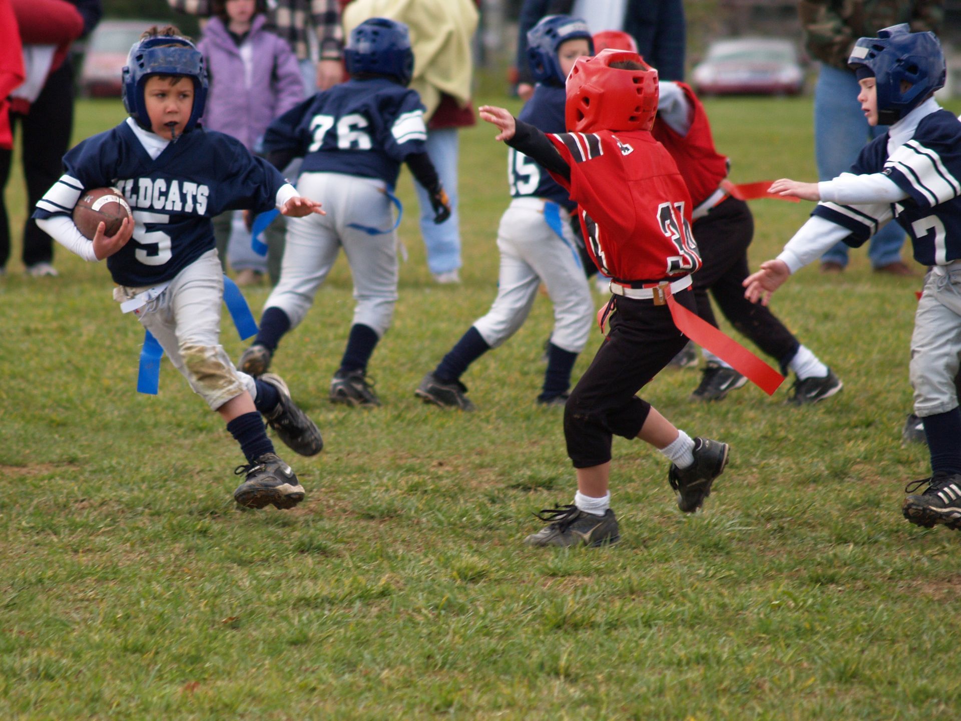 Football player in silver uniform runs with ball on a green field.
