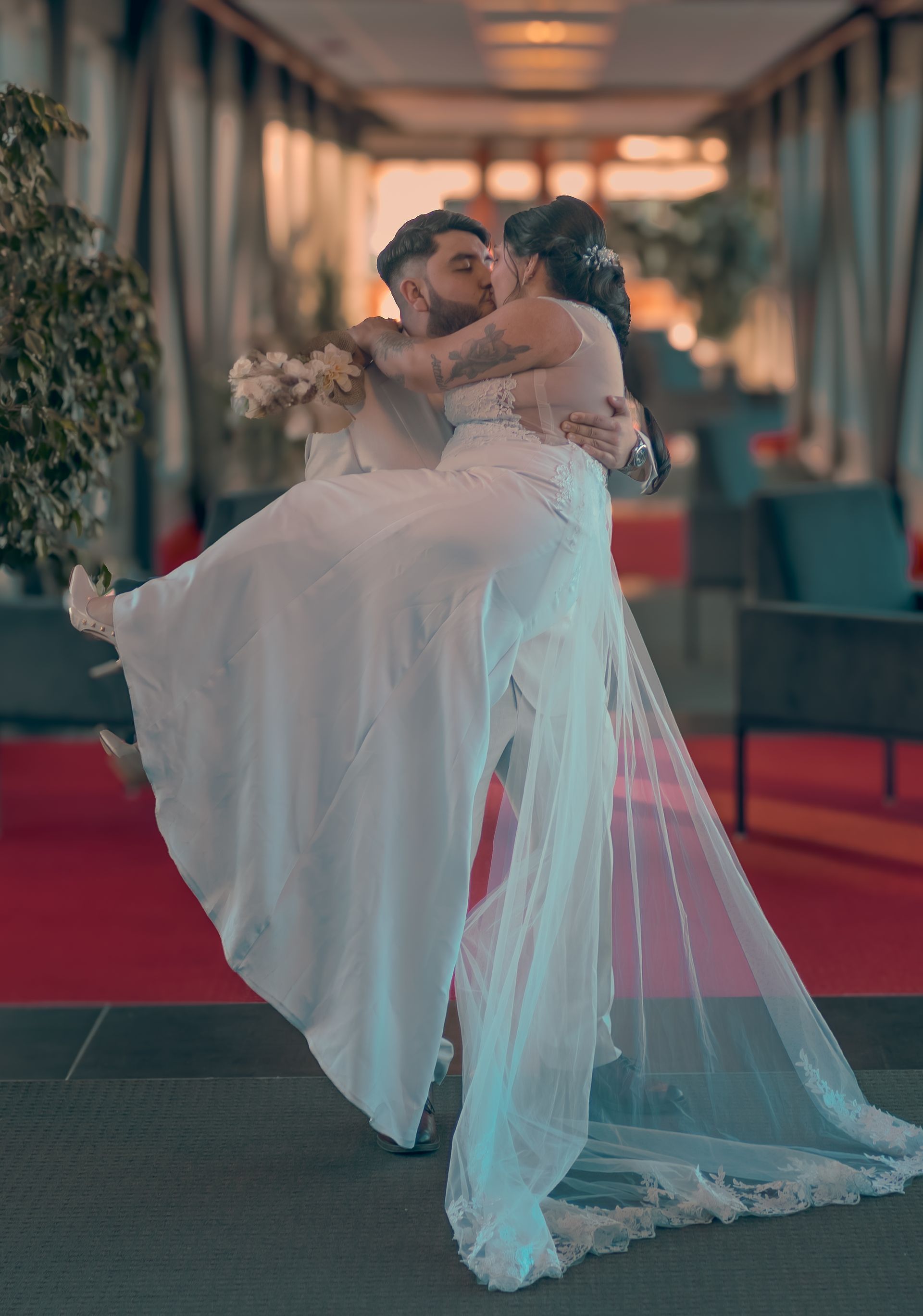 Un homme tient une mariée dans ses bras et l'embrasse.