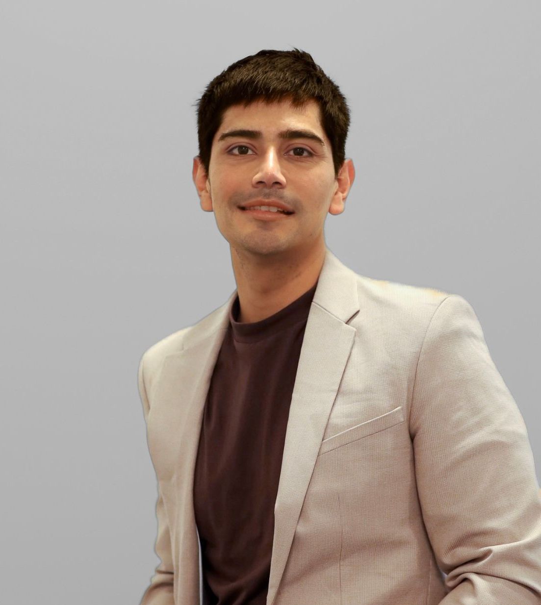 Un homme en costume et chemise marron sourit à la caméra