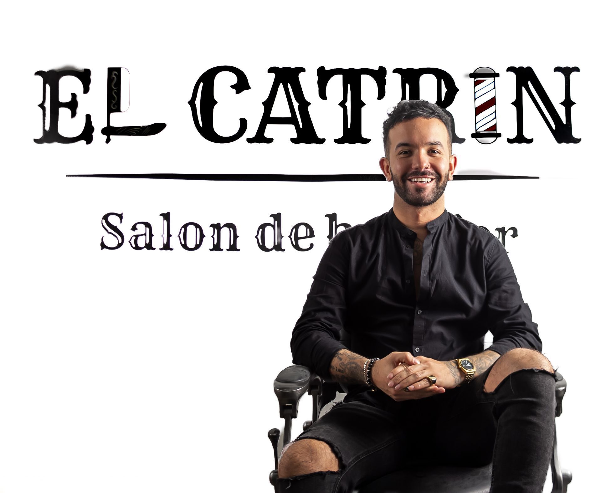 Un homme en chemise noire est assis sur une chaise de barbier sous le logo « El Catrin Salon de Bar ».