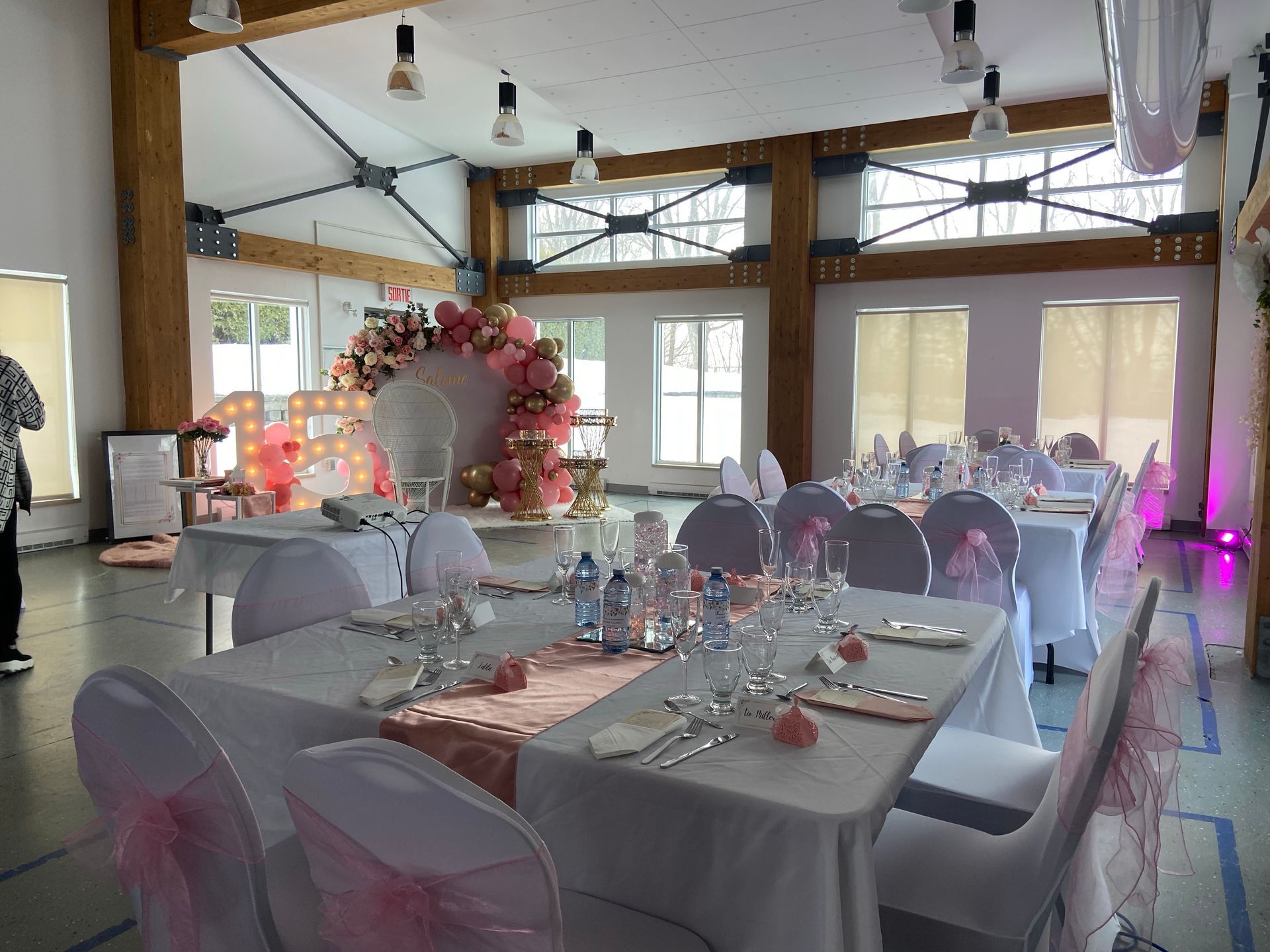 Une grande salle avec tables et chaises installées pour une réception de mariage.