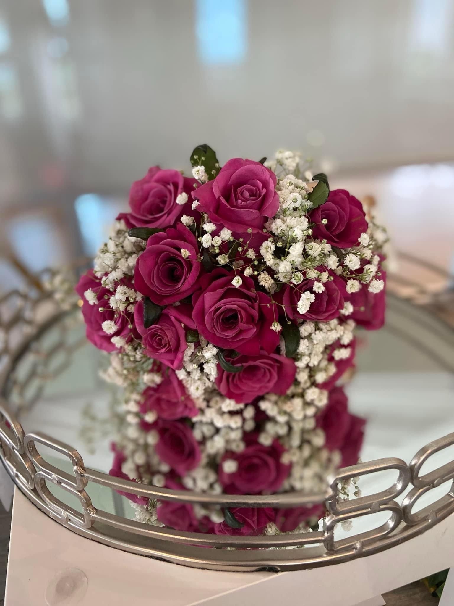 Un bouquet de roses roses et de gypsophile est posé sur un plateau en argent.