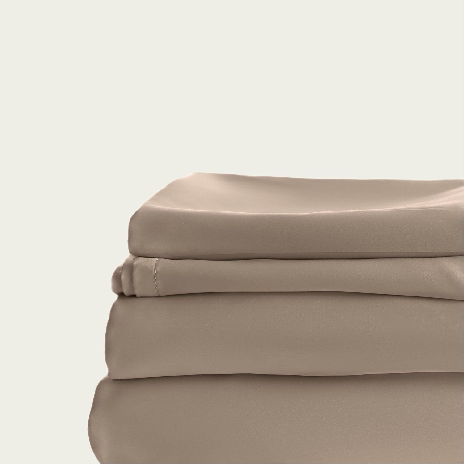 Une pile de draps beiges posés les uns sur les autres sur un fond blanc.