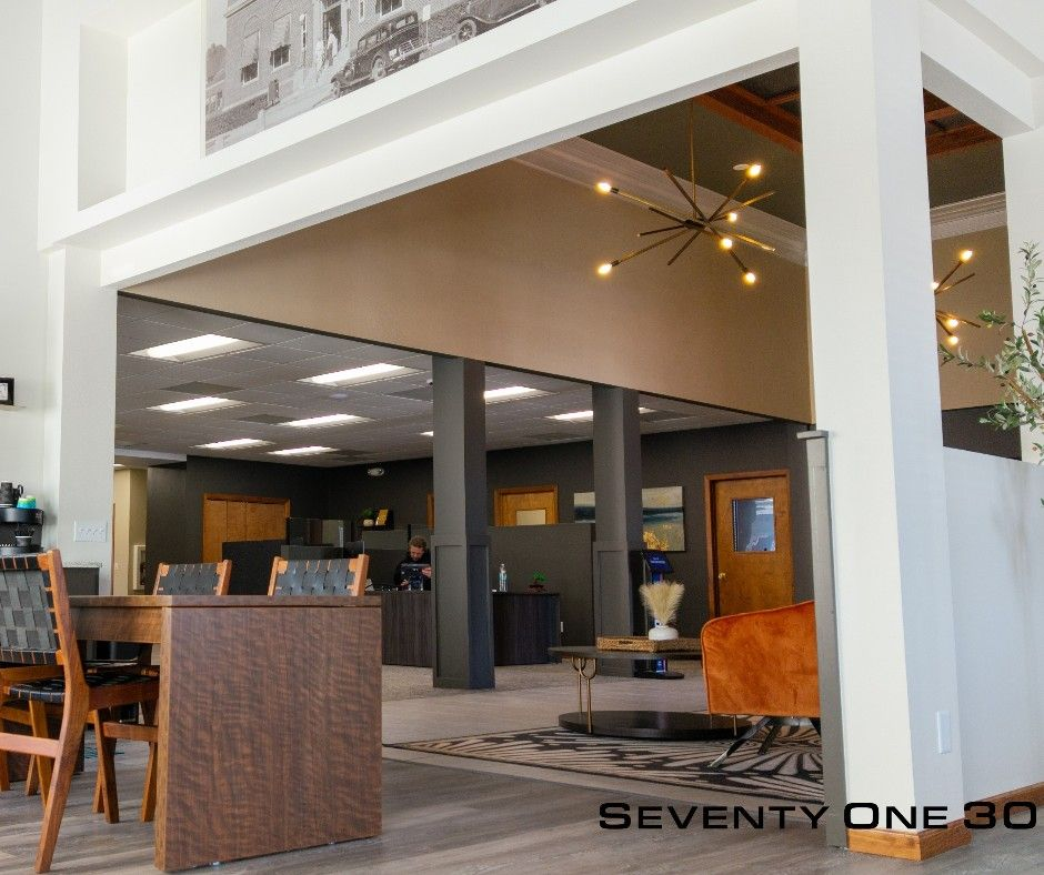 Open office interior with wooden furniture, gray and white walls, modern light fixture.