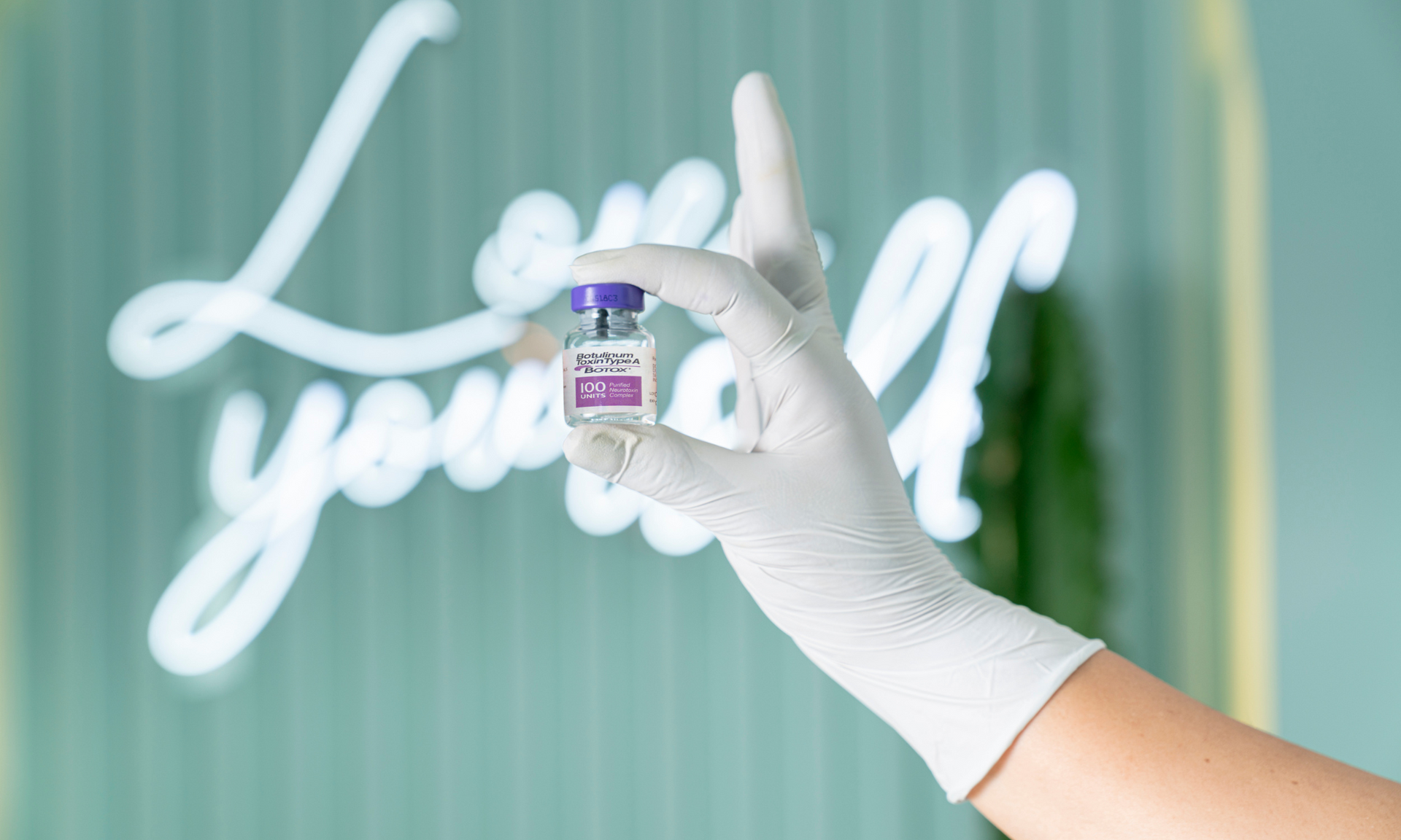 A person wearing a white glove is holding a bottle of Botox.