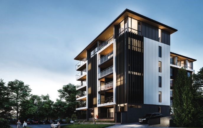 Modern multi-story apartment building with balconies. Black and white facade, set against a blue sky and green trees.