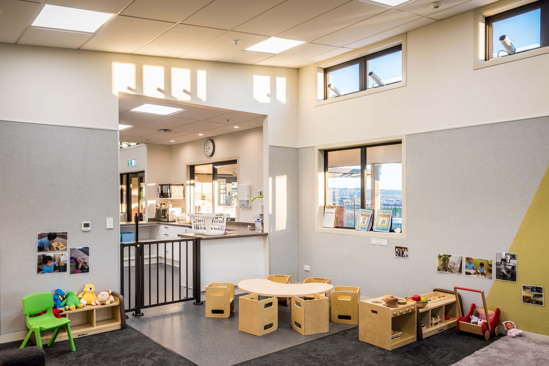 Interior of a child's play area. Features include wooden toys, a round table and chairs, and an open doorway to a counter area.