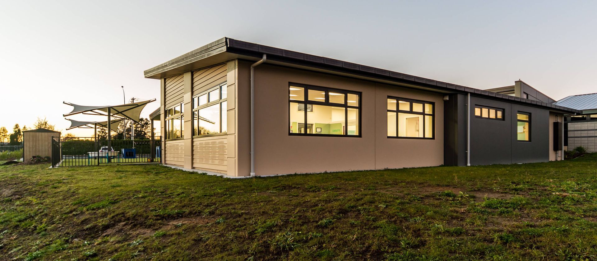 A modern building with large windows, set on a grassy area during daytime.