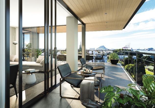 Balcony with modern furniture overlooking a cityscape and water on a bright, sunny day.