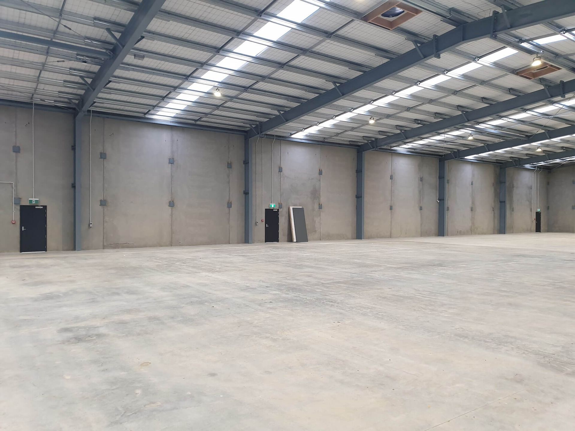 Empty industrial warehouse with concrete walls, floor, and metal roof.