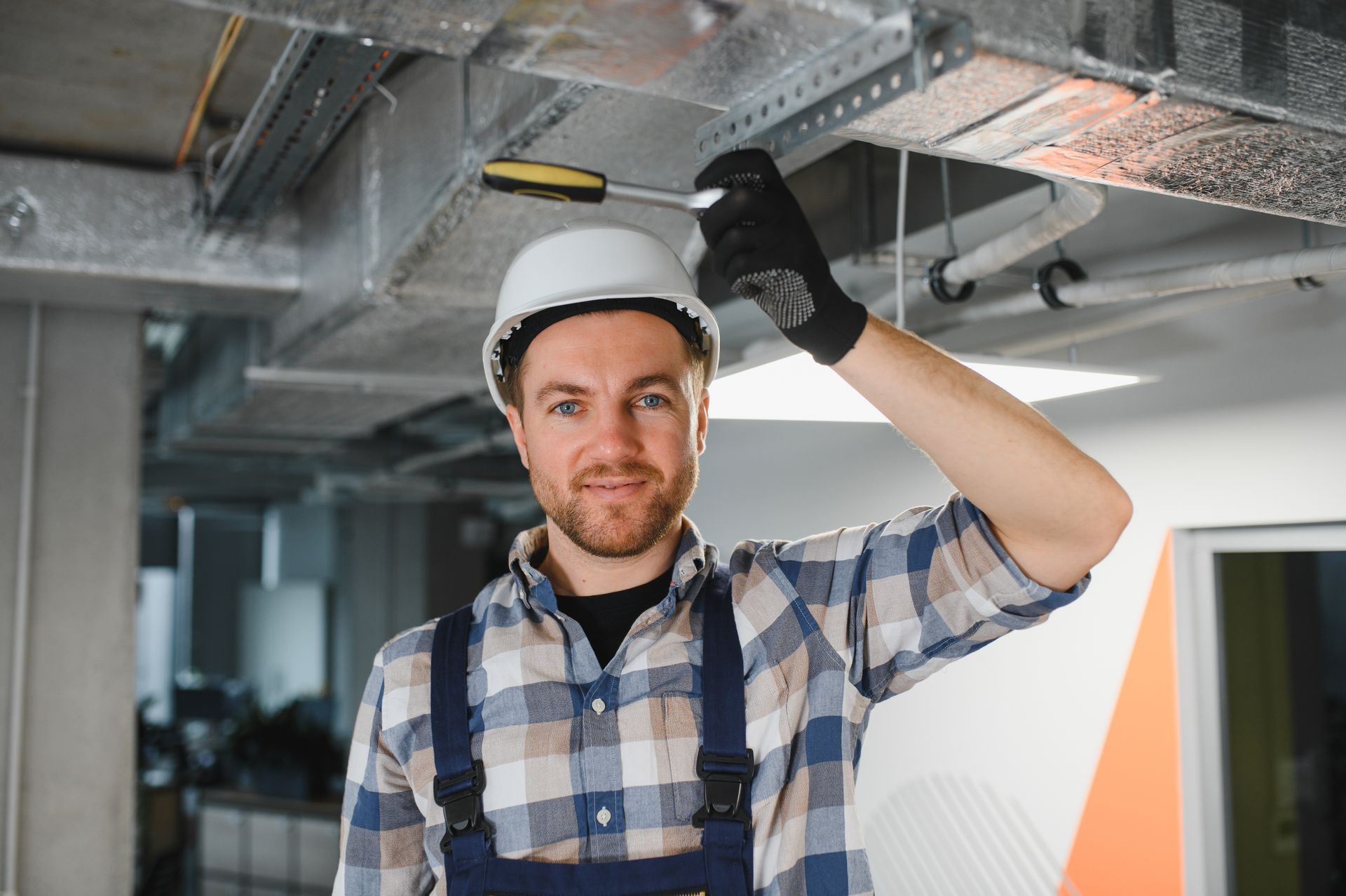 A heat pump technician installing a ducted system in an office building.
