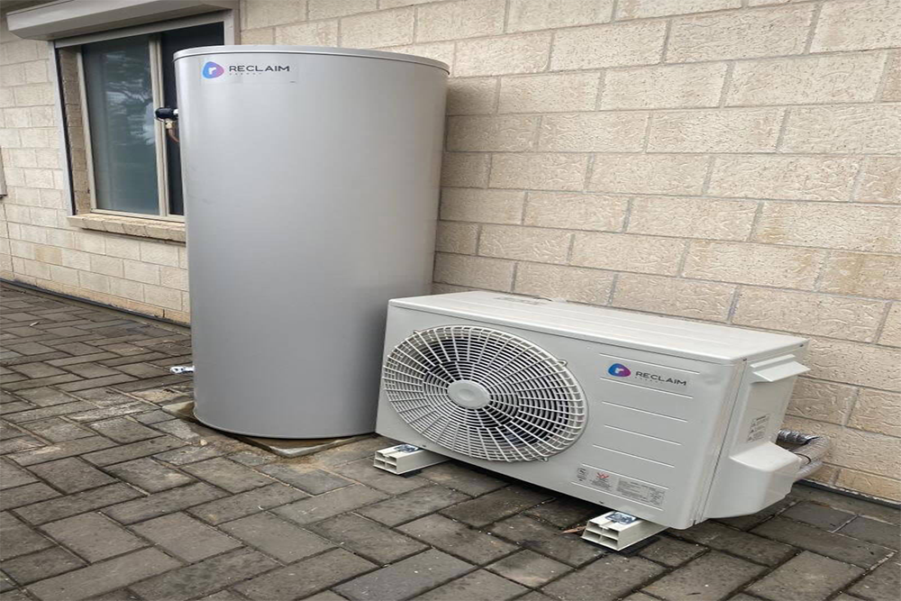 A water heater and a fan are sitting next to each other on a brick sidewalk.