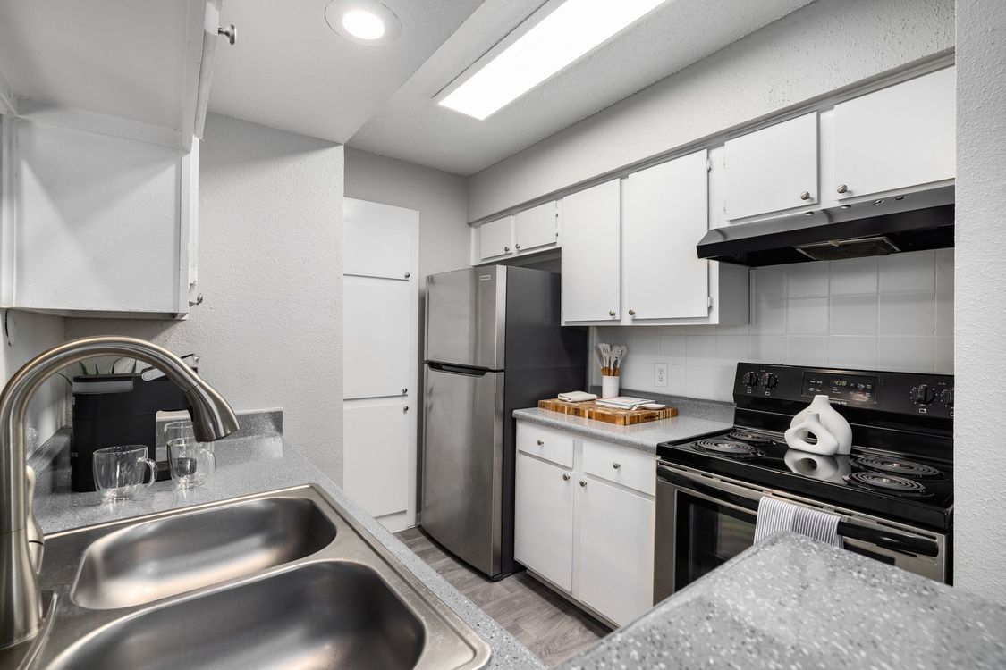 A kitchen with white cabinets and a black refrigerator.