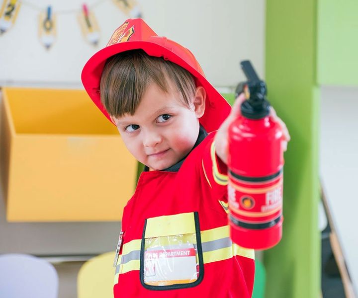 bambino con estintore giocattolo vestito da pompiere