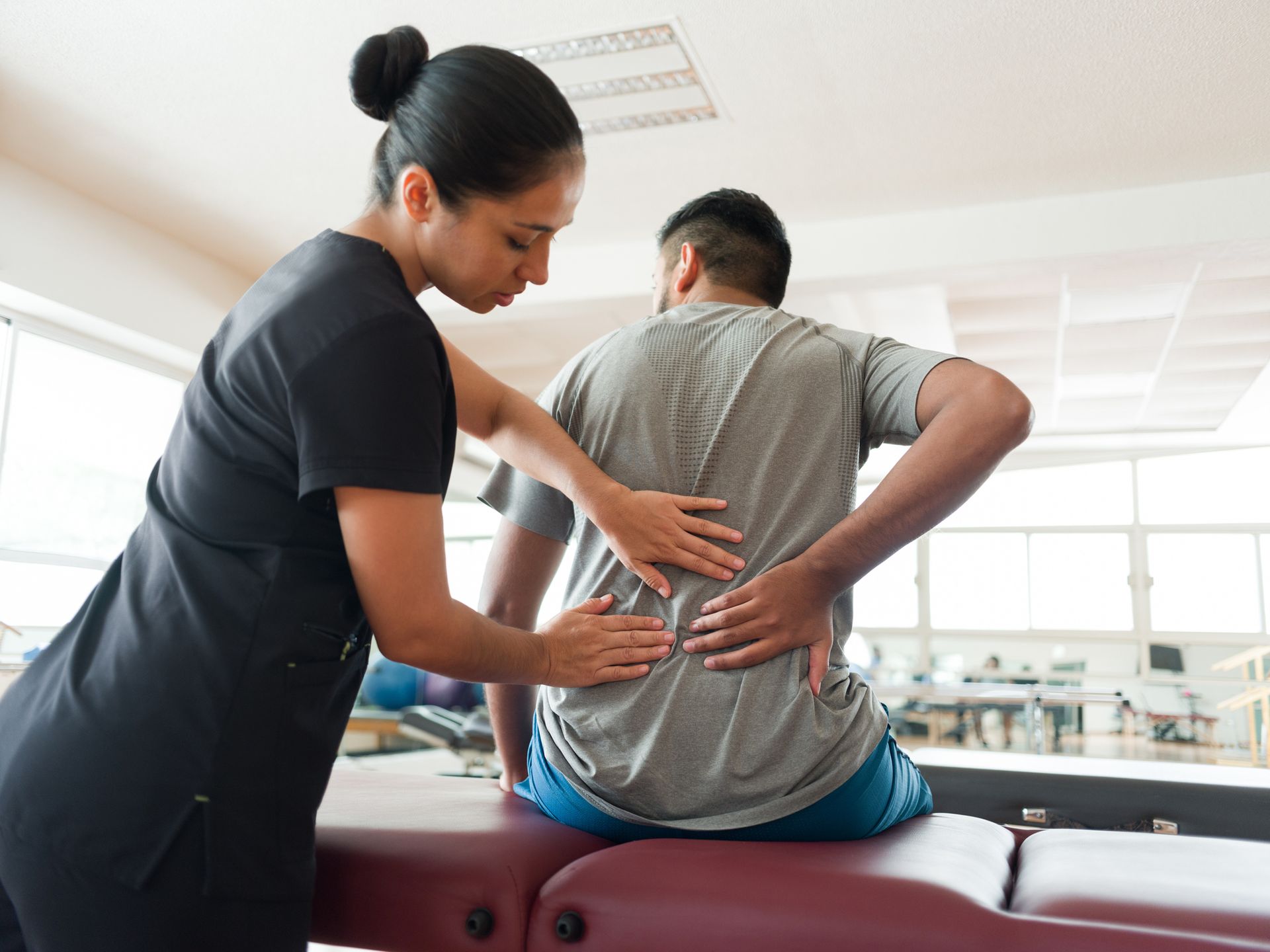 Therapist providing back pain physical therapy treatment in Philadelphia, PA, massaging patient’s ba