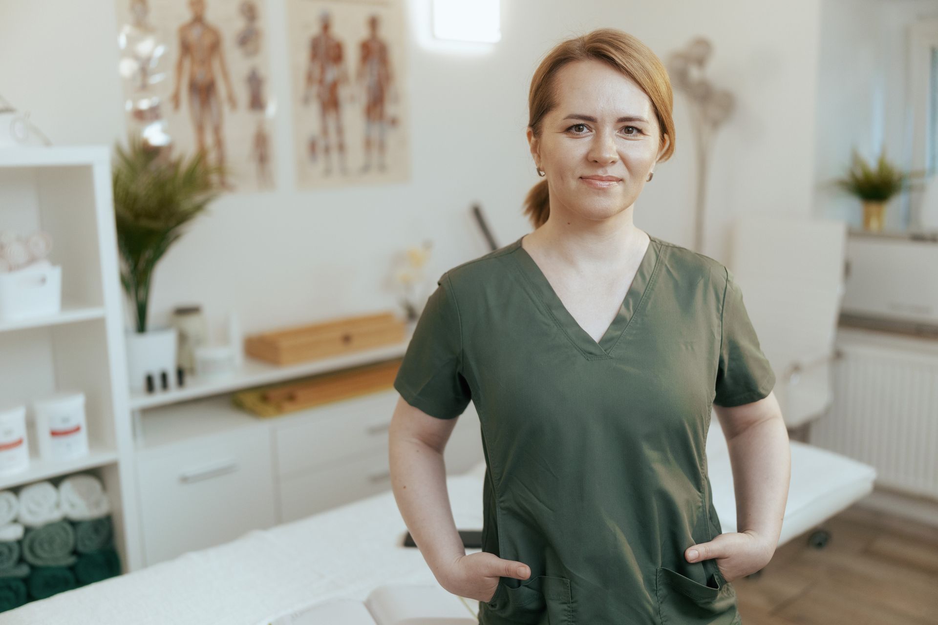 A female medical massage therapist in a massage cabinet looking at the camera.