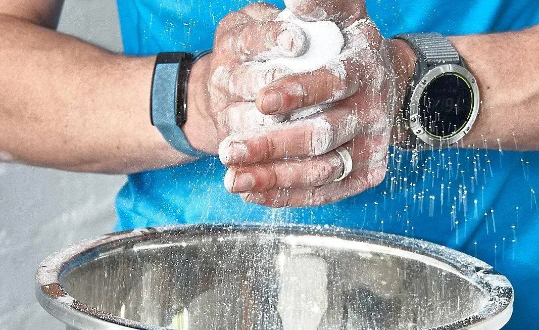 A man is pouring flour into a metal bowl.