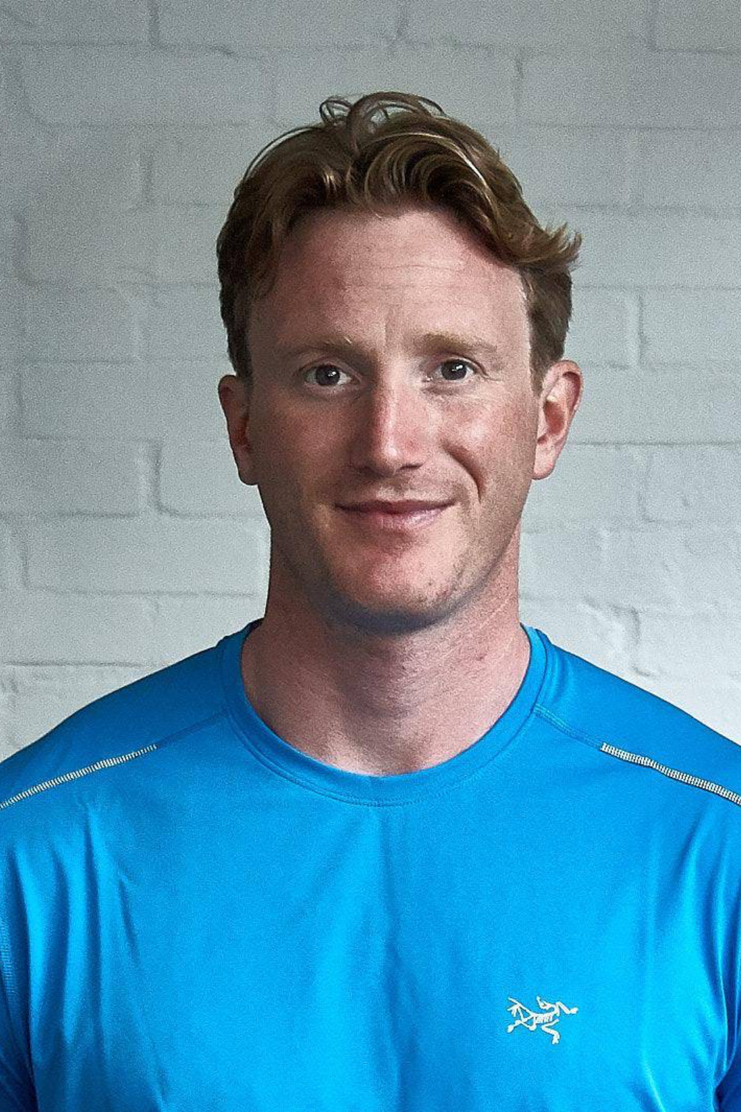 A man wearing a blue shirt is smiling for the camera.