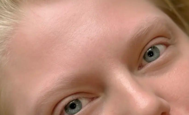 Close-up of a person's face with blue eyes and fair skin looking toward the viewer.