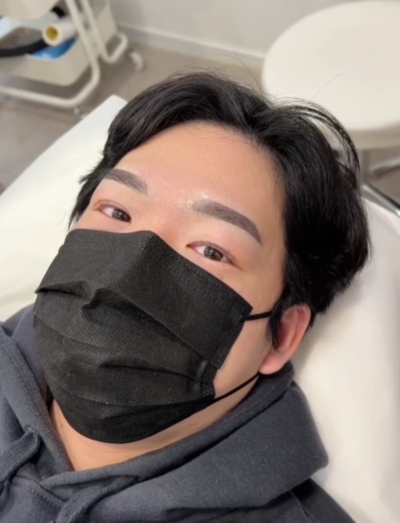 Woman wearing a mask with dark hair, eyebrows, and eyeliner.