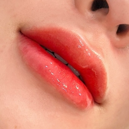 Close-up of glossy, red lips, slightly parted, with teeth visible.