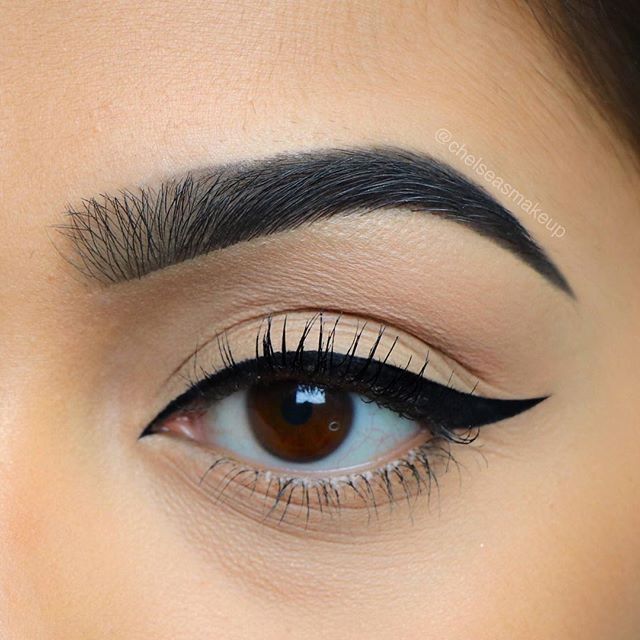 Close-up of a person's eye with neatly shaped eyebrows and a light-colored face mask.