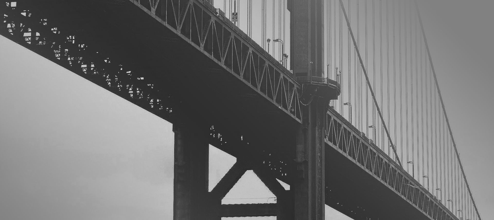 a black and white photo of a bridge with a cloudy sky in the background .