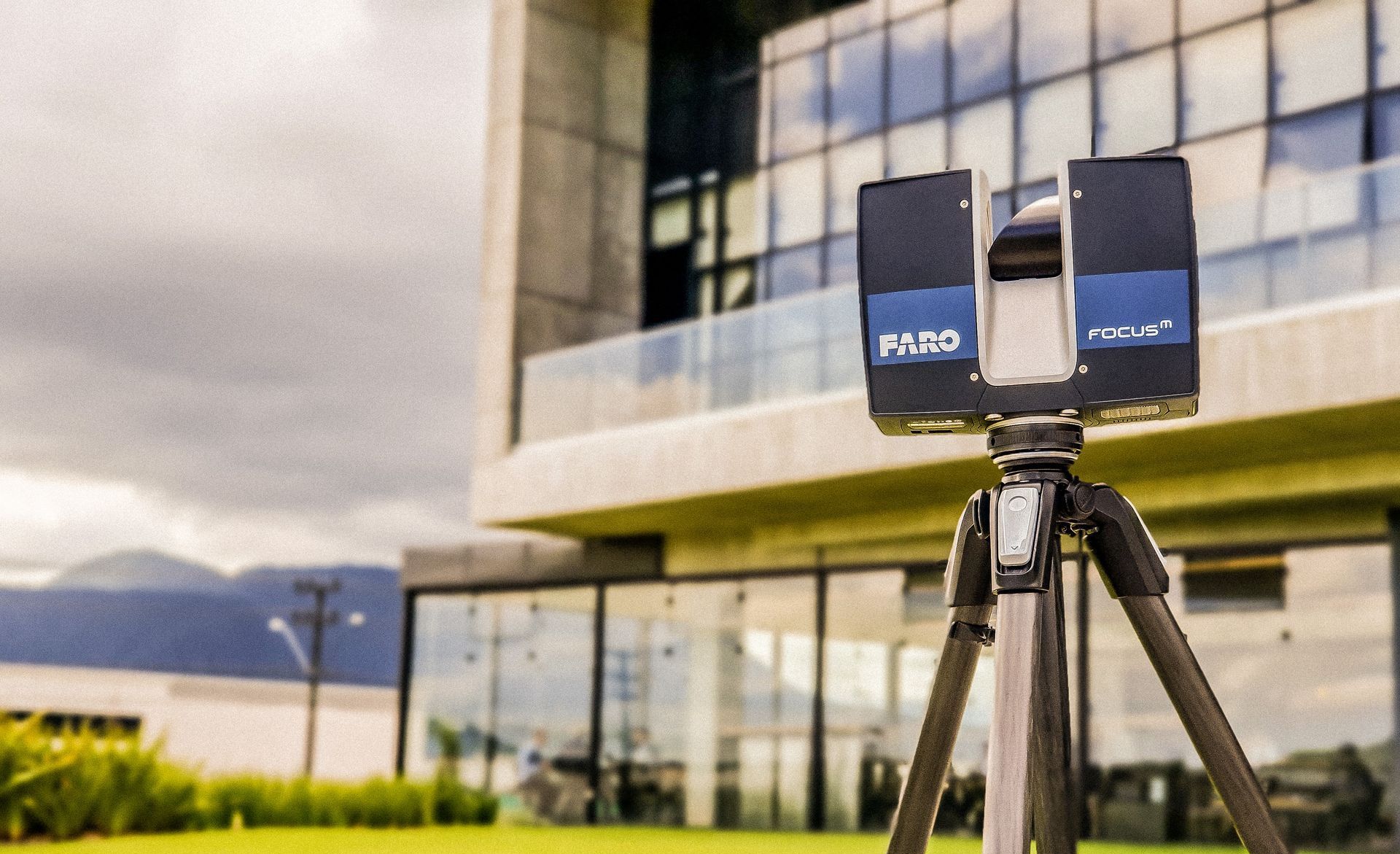 A 3d scanner is sitting on a tripod in front of a building.