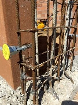 Construction site: Steel rebar cage around a concrete pillar, ready for concrete pouring.