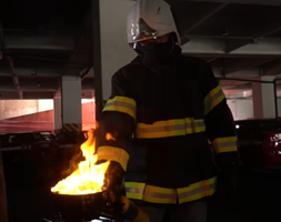A flame test experiment showing a glowing orange flame produced by a wire being held over a Bunsen burner in a lab.