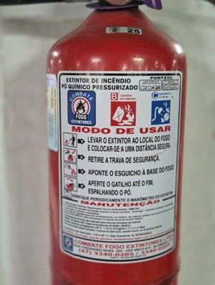 A red fire extinguisher with a label explaining its usage instructions, safety icons, and maintenance contact details.