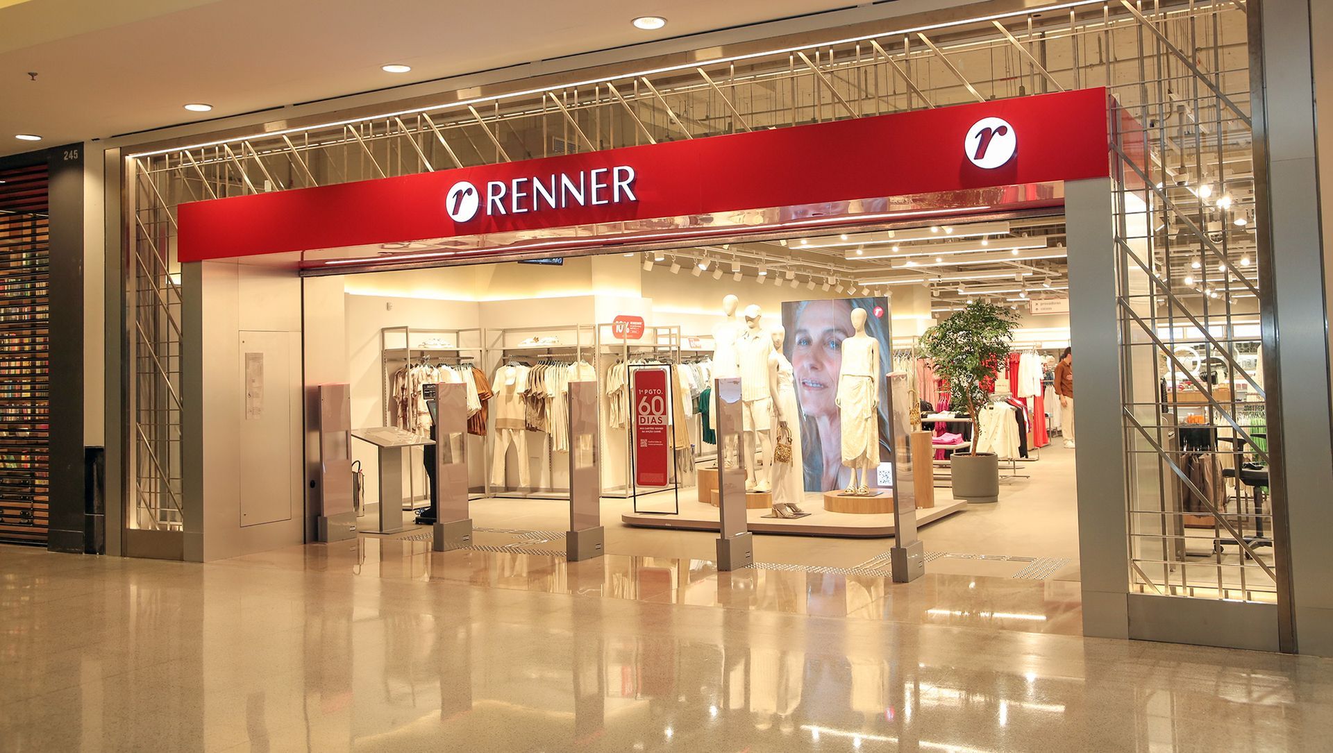 Entrance of a Renner clothing store in a brightly lit shopping mall, featuring a red sign and large display windows.