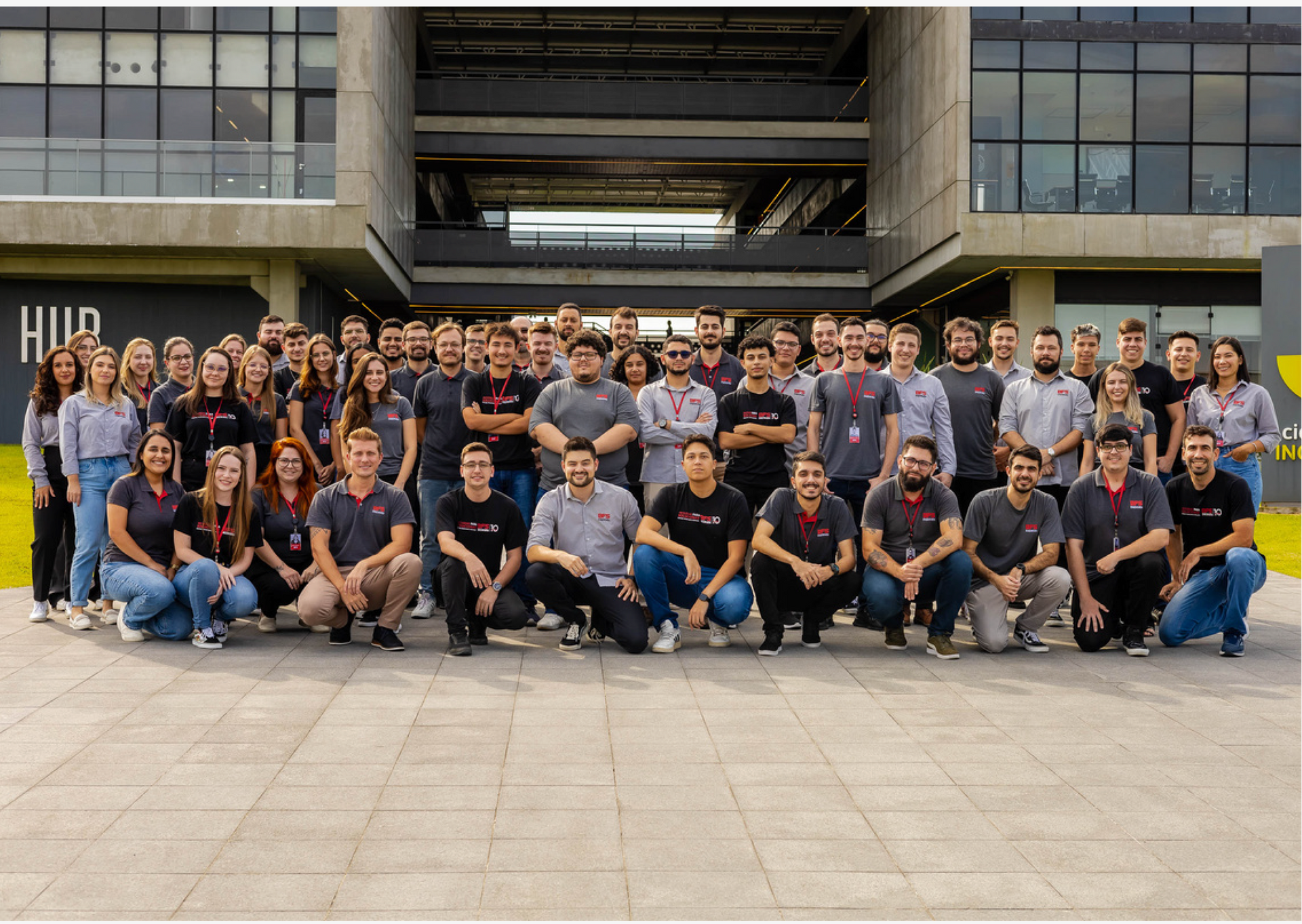 Um grande grupo de pessoas está posando para uma foto em frente a um prédio.