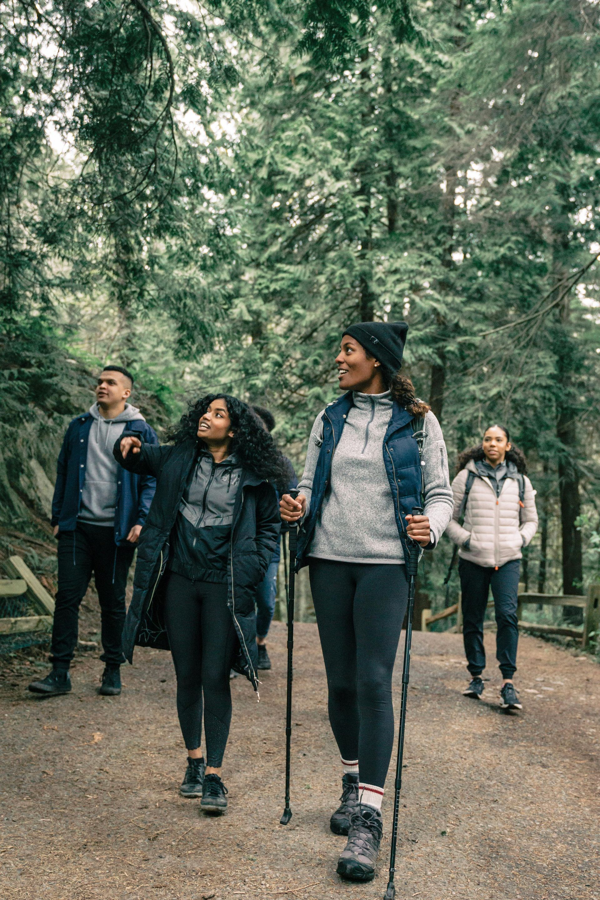 Group of people hiking on a forest trail, smiling and looking up.