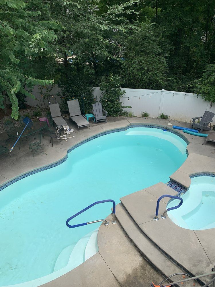 A large swimming pool with stairs and chairs around it