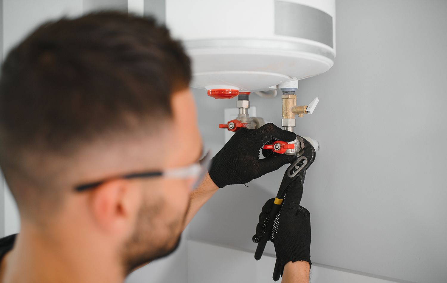 Technician using a power drill to repair a ceiling smoke detector under a white fixture