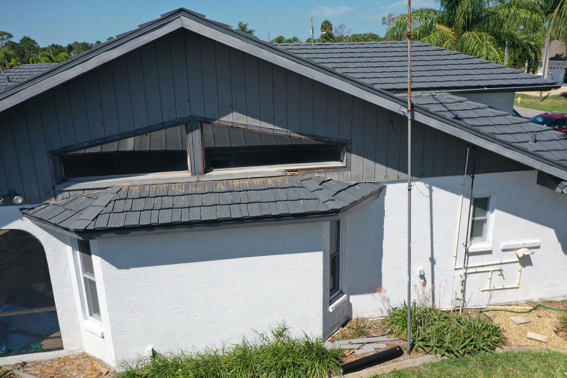 An aerial view of a white house with a gray roof.