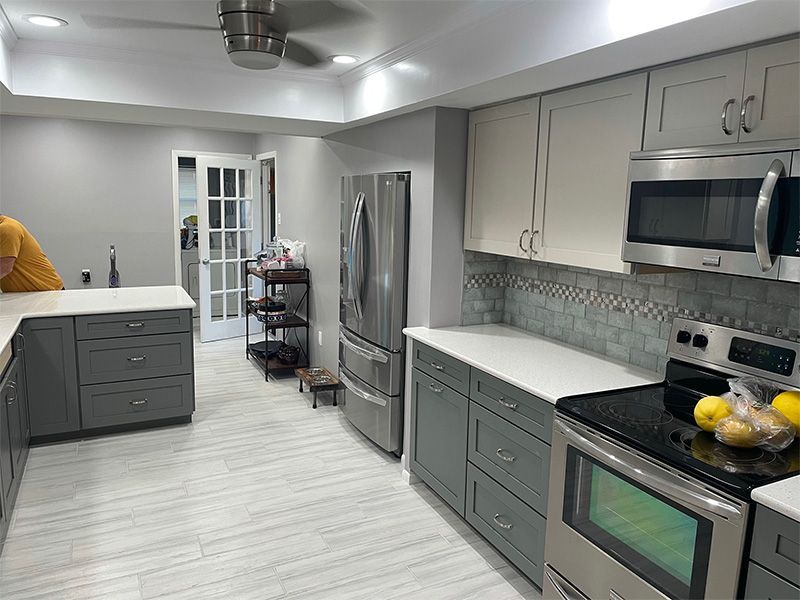 Modern kitchen: gray and white cabinets, stainless steel appliances, light gray walls, and white countertops.