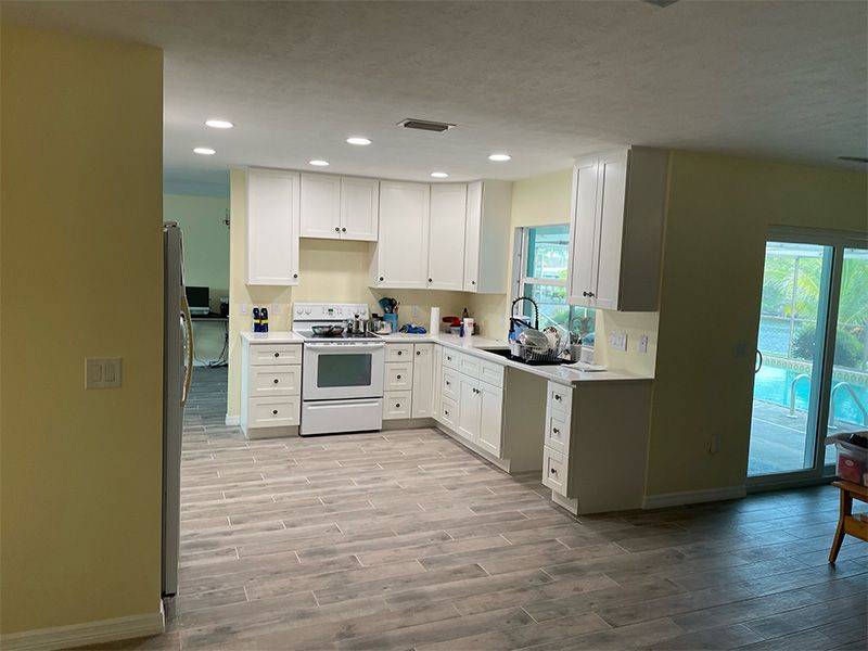 White kitchen with a stove, cabinets, and counter next to a sliding door leading to a pool.