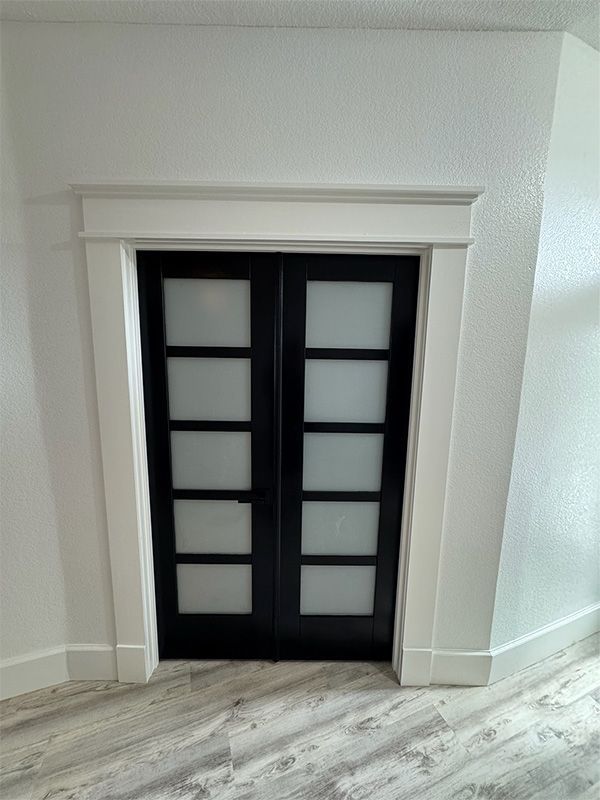 Black glass panel double doors with white trim in a white room.