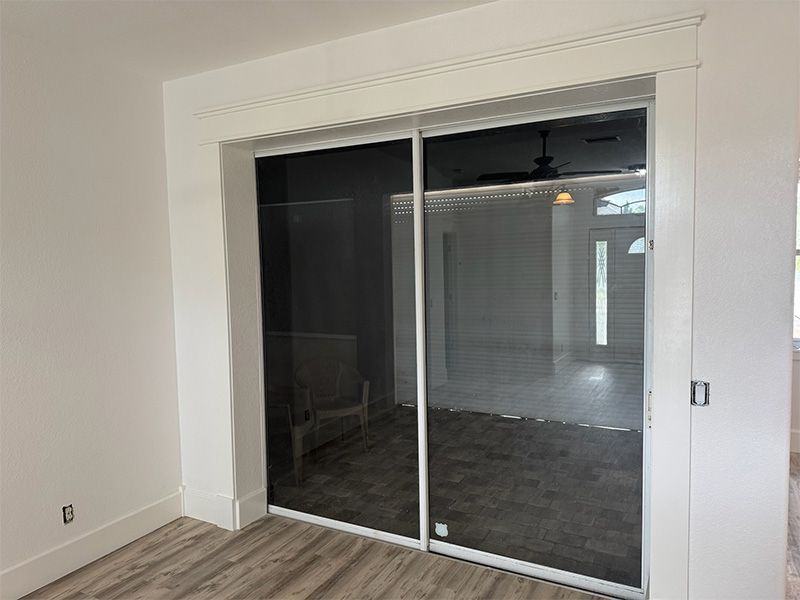 White framed sliding glass doors with a dark screen and trim in a room with light flooring.