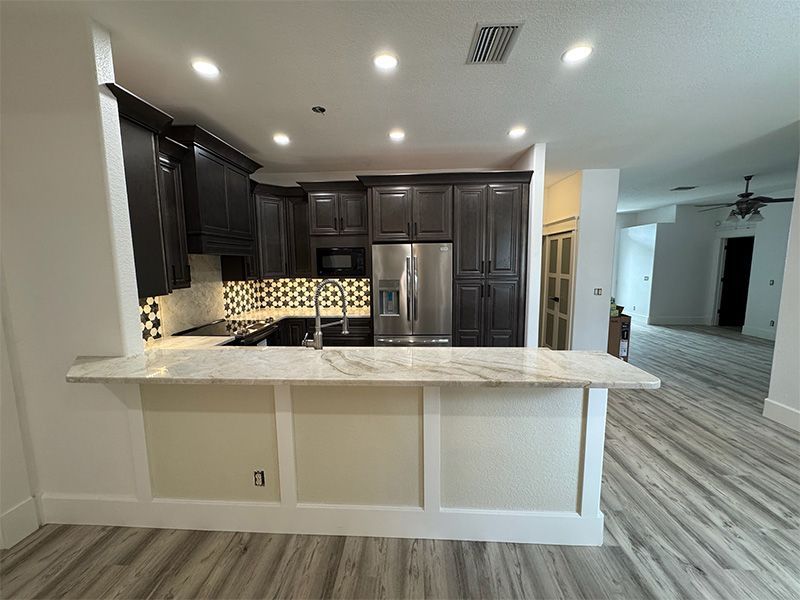 Modern kitchen with dark cabinets, stainless steel appliances, and a granite countertop breakfast bar.